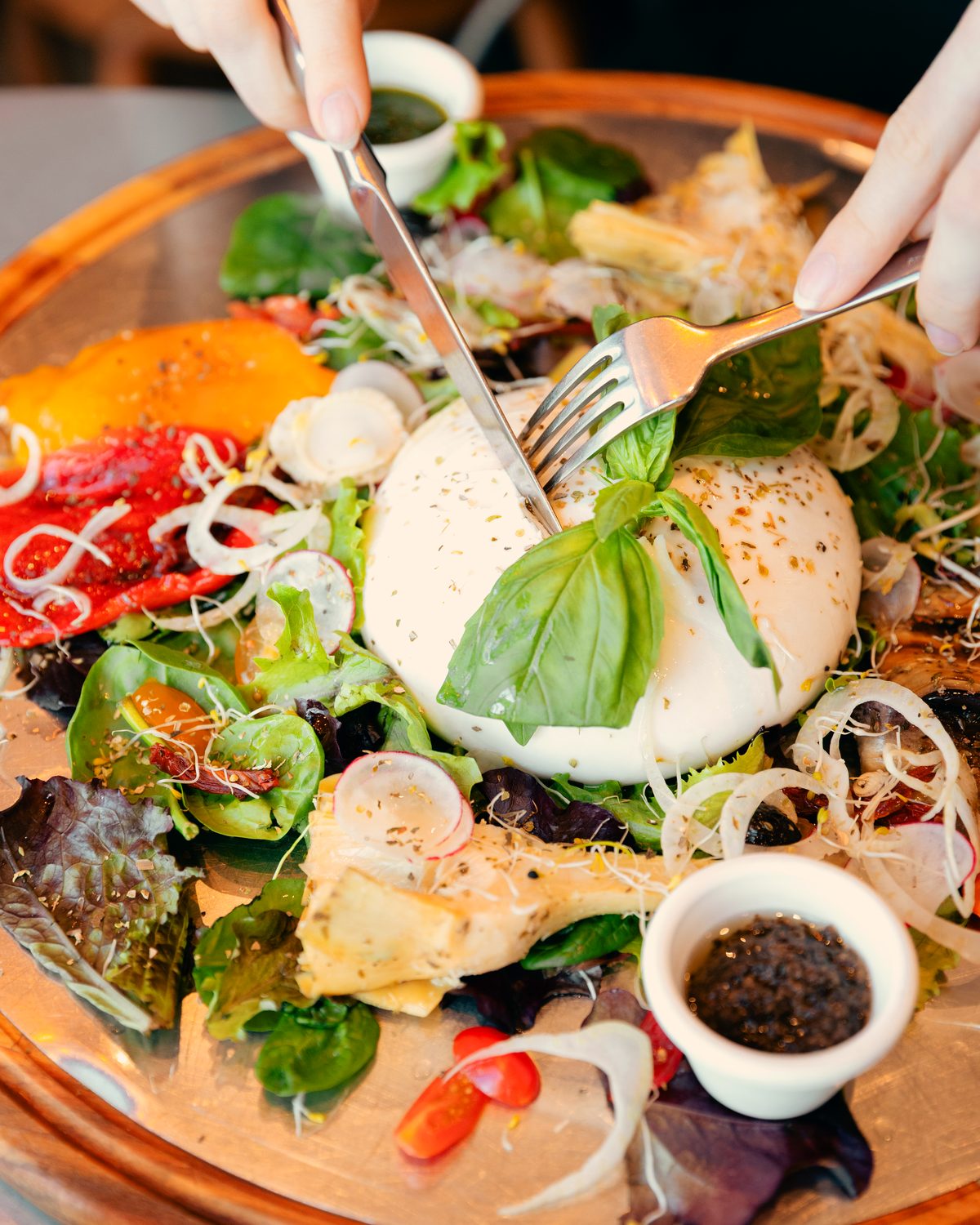 Grande assiette de burrata crémeuse sur un lit de légumes et de jeunes pousses.