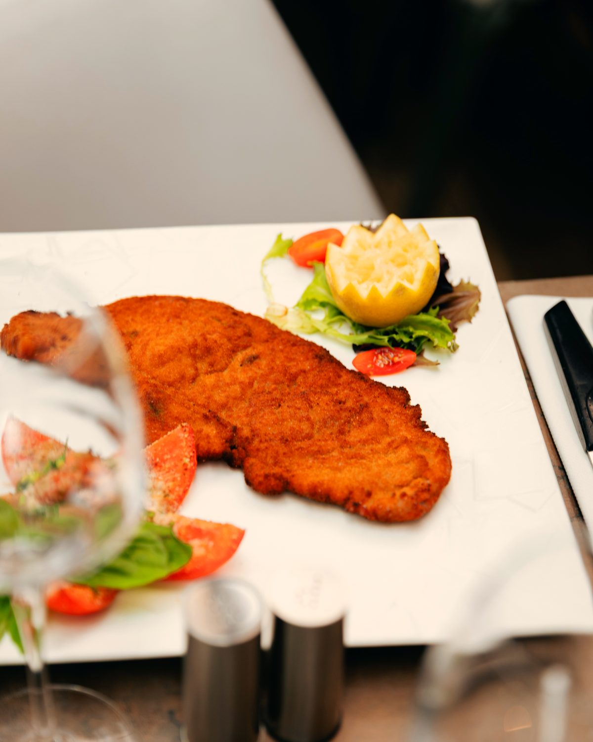 Escalope milanaise panée, servie avec citron et salade de tomates.